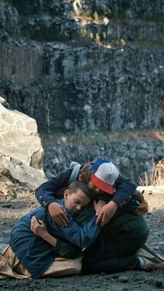 two people hugging each other while sitting on the ground