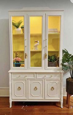 a white china cabinet with yellow glass doors