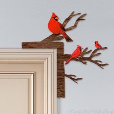 three red birds sitting on top of a tree branch next to a white door frame