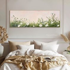 a painting on the wall above a bed in a room with white walls and pillows