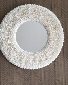 a white circular mirror sitting on top of a wooden table next to a brown wall