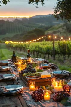 an outdoor dinner table with candles, plates and wine bottles in the middle of it