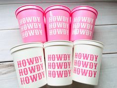 four pink plastic cups with the words howdy hodwy on them are lined up in a row