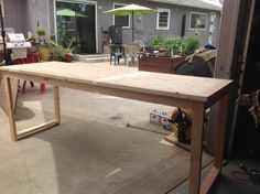 a wooden table sitting in the middle of a yard with an umbrella on top of it