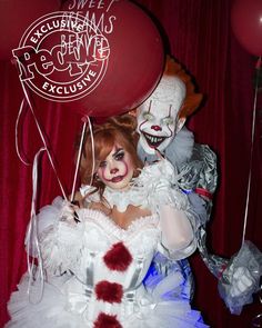 a creepy clown holding two balloons in front of a red curtain