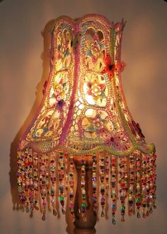 a lamp that is on top of a wooden stand with beads hanging from it's sides