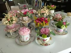 a table topped with tea cups and saucers filled with different types of flowers on top of each other