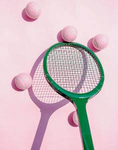 a green tennis racket surrounded by pink balls