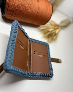 an open wallet sitting on top of a table next to a spool of thread