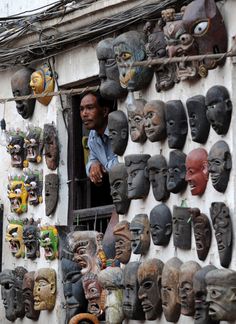 a man is looking out the window of his shop with many african masks on display