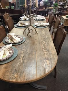 a wooden table with plates and place settings on it