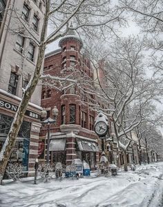 an old brick building is surrounded by snow and bare trees on a snowy day in the city