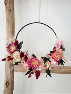 a wreath with flowers and feathers hanging on a wall