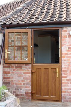 an open wooden door in front of a brick building with brown shingles on the roof