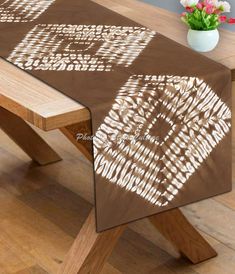 a wooden table topped with a brown and white table cloth next to a potted plant