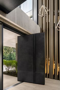 an open black door in front of a wooden wall and stairs with lights hanging from the ceiling