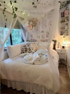 a white bed with lots of pillows and stuffed animals on top of it in a bedroom