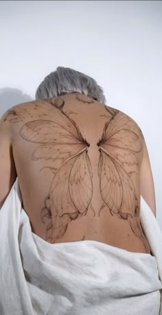 the back of a woman's body covered in a white towel with butterflies drawn on it