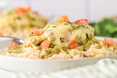 a white plate topped with rice covered in cheese and veggies next to a fork