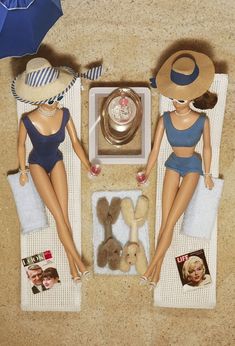 two dolls are sitting on the beach in their bathing suits and hats with teddy bears