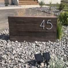 a wooden box with the number 45 on it in front of some rocks and plants