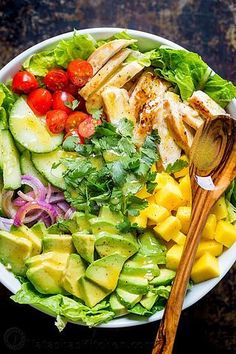 a salad with chicken, avocado, tomatoes and cucumber in it