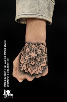 a man's hand with a flower tattoo on it