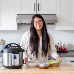 a woman standing in front of an electric pressure cooker with ingredients on the counter