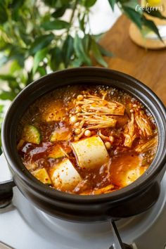 a bowl of soup with tofu and beans in it sitting on a stove top