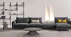 a modern living room with grey couches and two lamps on the wall above them