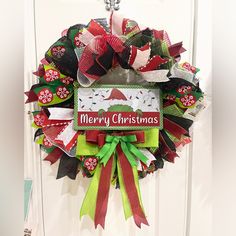 a christmas wreath hanging on a door with the words merry christmas written on it's front