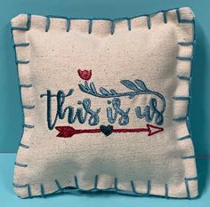 this is us embroidered pillow with an arrow on the front and blue trimmings