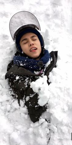 a young boy is laying in the snow