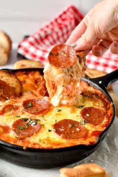 a person is taking a slice of pepperoni pizza from a skillet