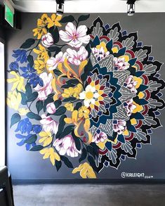 a large flower painting on the side of a wall in a room with two lights