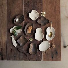 a wooden table topped with white dishes and spoons