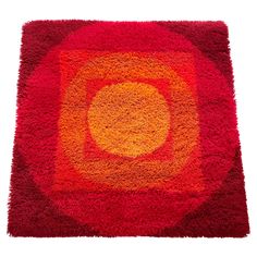 a red rug with an orange circle in the center on a white background, it appears to be part of a piece of art