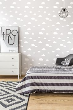 a bed room with a neatly made bed next to a dresser and wallpaper on the walls