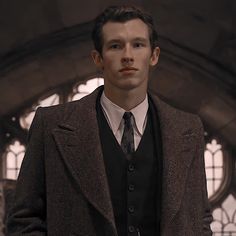 a man wearing a suit and tie standing in front of a building with arched windows