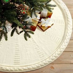 two wrapped presents sitting on top of a white round table next to a christmas tree