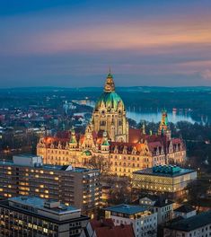 the city is lit up at night with many lights on it's spires