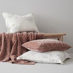 three pillows stacked on top of each other in front of a wooden chair with a blanket draped over it