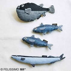 three fish made out of jeans sitting on top of a table