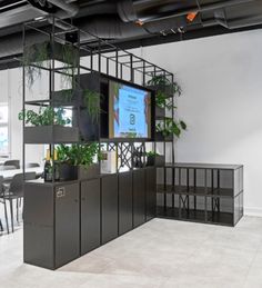 an office with plants on the shelves and tables in front of them, along with a flat screen tv