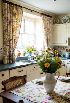 a vase with flowers sitting on top of a table in front of a kitchen window