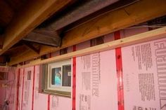 an unfinished room with red tape on the wall and framed pictures hanging from the ceiling