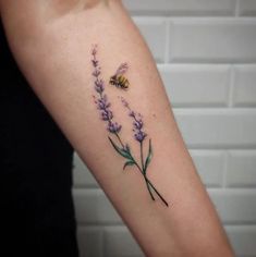 a woman's arm with lavender flowers and a bee tattoo on the left forearm