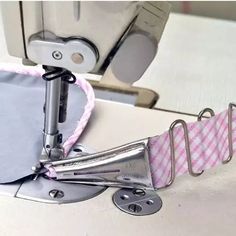 the sewing machine is next to the pink and white ribbon that has been sewn