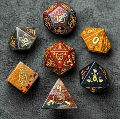 six different colored dices sitting on top of a gray surface with gold and red designs