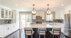 a large kitchen with white cabinets and marble counter tops, an island in the middle